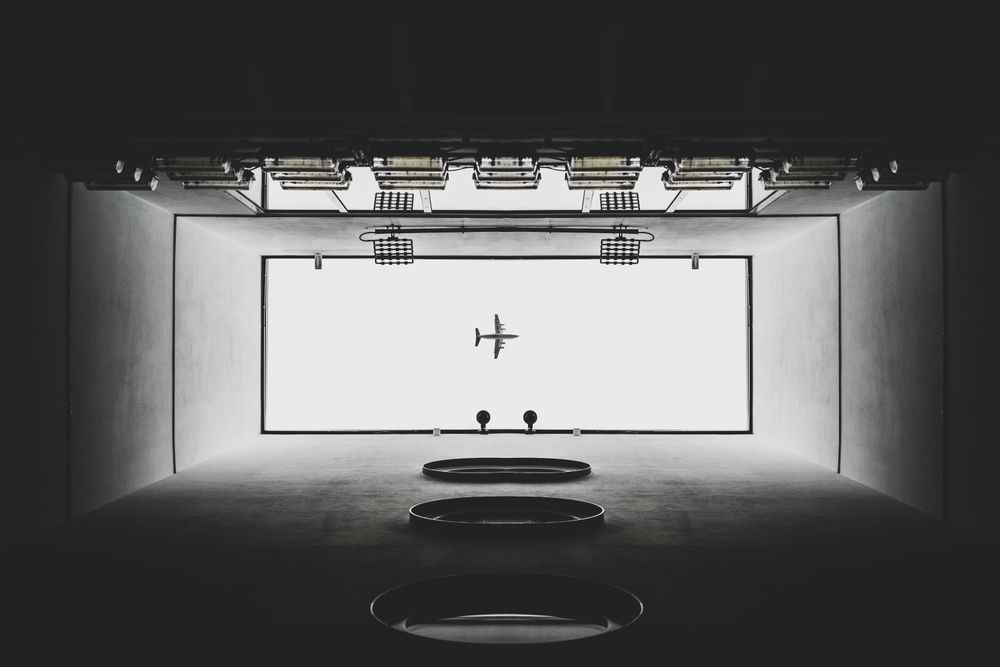 Airplane above building in grayscale