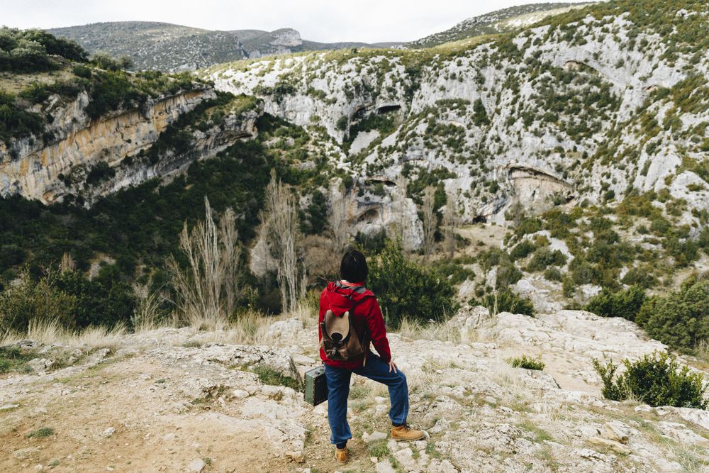 Woman with backpack on high cliff