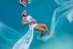 Pregnant woman in wreath and dress underwater