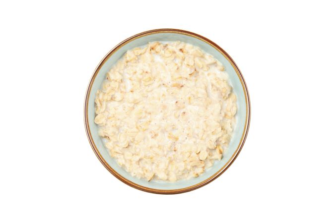 Bowl with cooked oatmeal isolated on plain background
