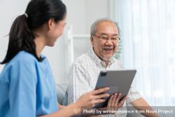 Patient smiling as medical professional shows him something on tablet 4AxYq5
