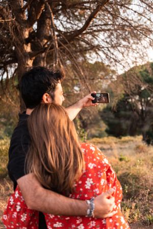 Couple kissing and taking photo outdoors