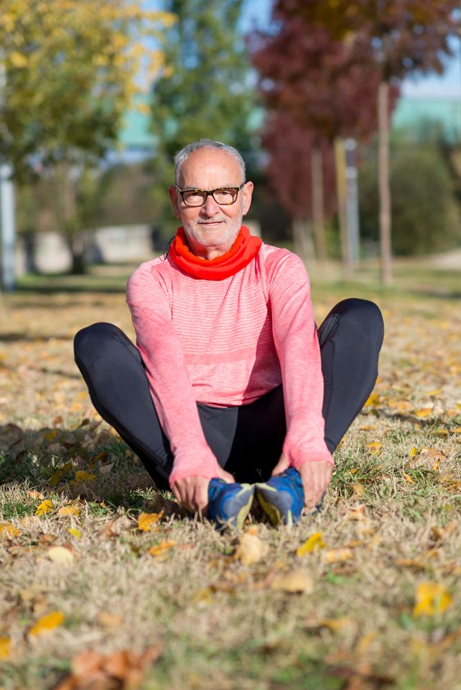 Older male stretching legs in park