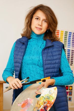 Female artist in green shirt holding paint palette