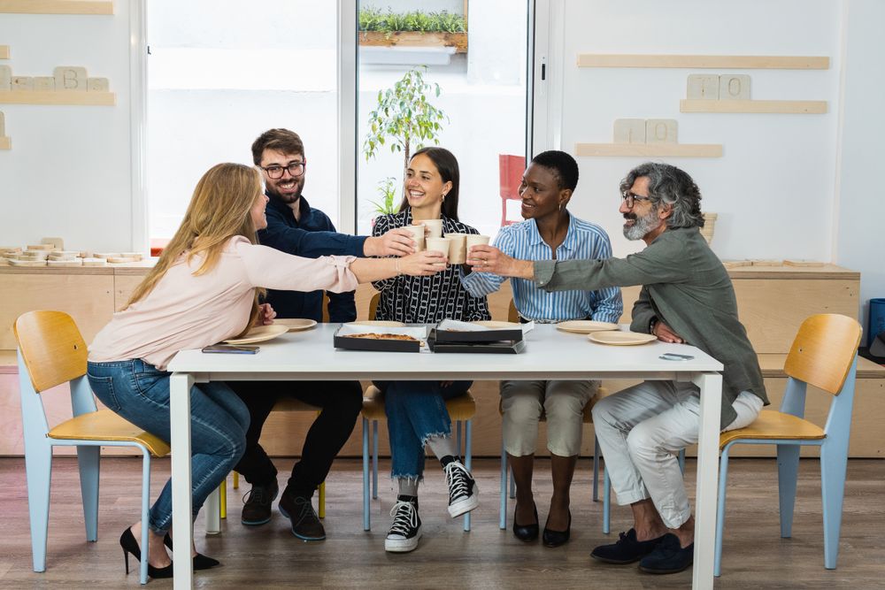 Diverse colleagues having lunch together in kitchen of office