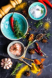 Spices, herbs and salt in teal bowls on counter with copy space