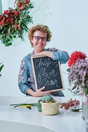 Happy woman demonstrating chalkboard in floral shop