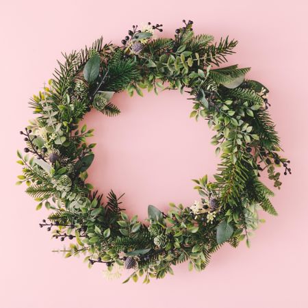 Christmas wreath made of branches on pink background
