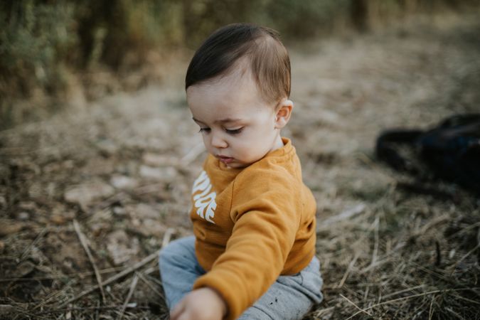 Baby boy sitting on a walking trail outside