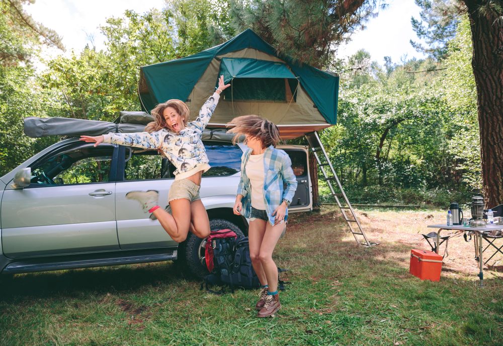 Young women having fun in campsite with 4x4 on background