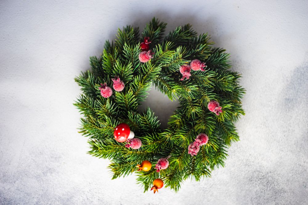 Top view of Christmas wreath with red berries on marble counter