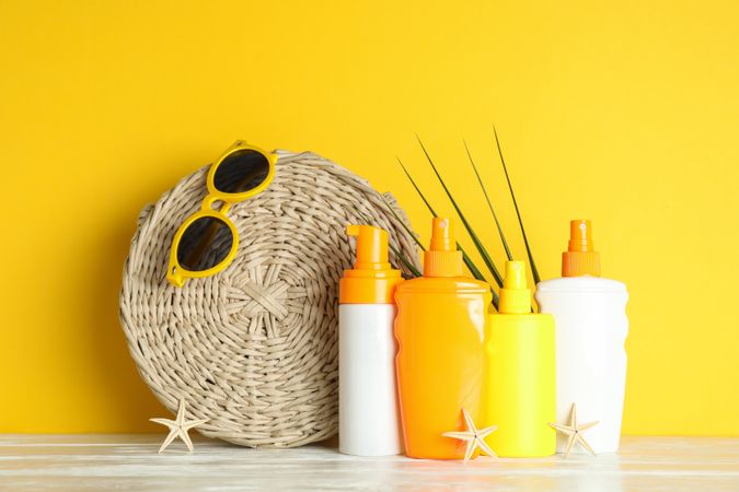 Summer vacation accessories on white table against color background, space for text. Safe tan