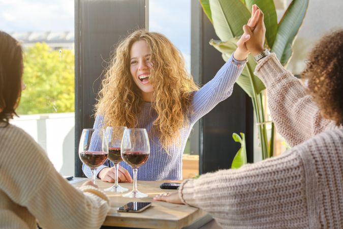 Laughing woman with wine giving high five