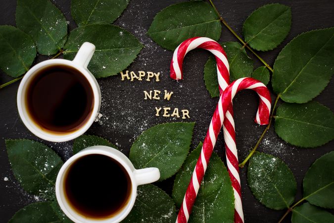 inscription of new year on a board with sprigs leaves and red candy