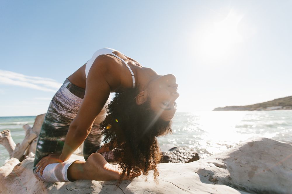 Sportive woman performing yoga posture on stones in nature