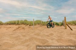 White male riding bicycle along sandy dune 5QDwG0