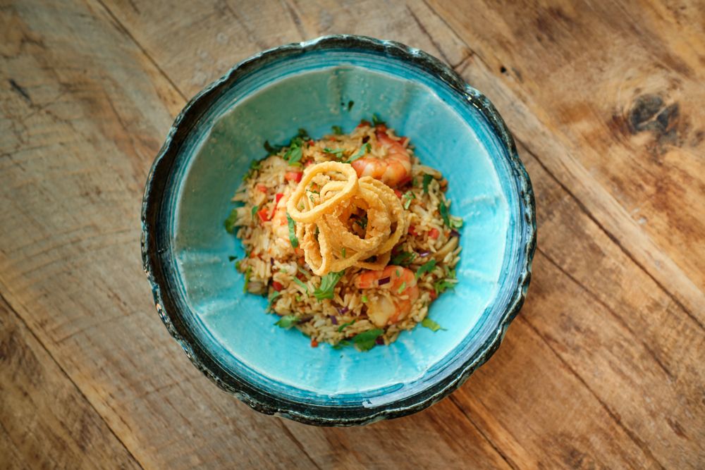 Bowl of delicious fried rice with shrimps on wooden table