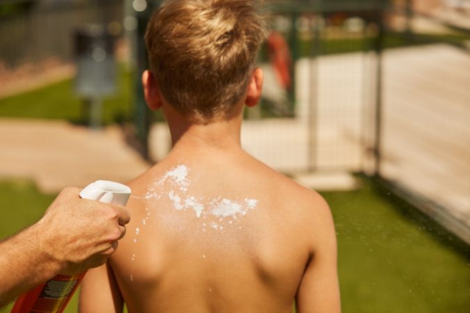 Faceless man applying sun cream on kid