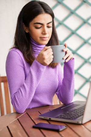 Woman sitting on deck working on computer, vertical