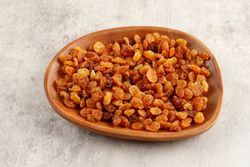 Wooden bowl of golden raisins on marble table