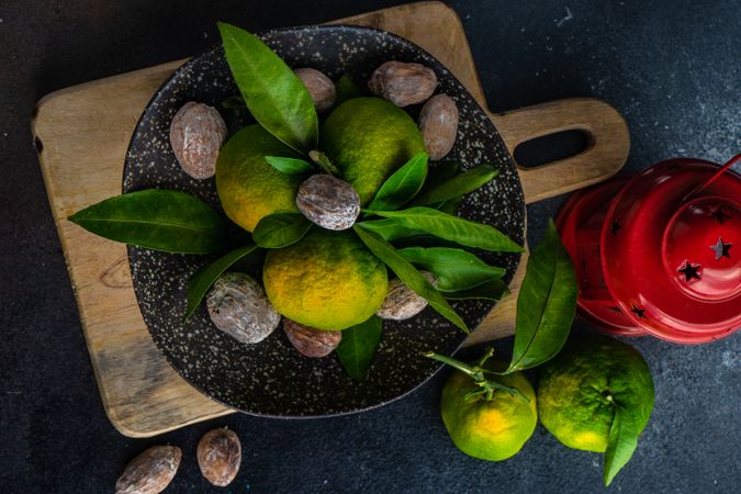 Top view of green tangerines in grey ceramic bowl with walnuts