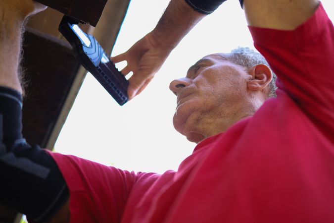 An older man in late sixties working on his roof.