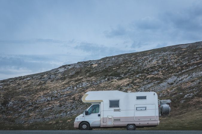 Camper near hill on cloudy day