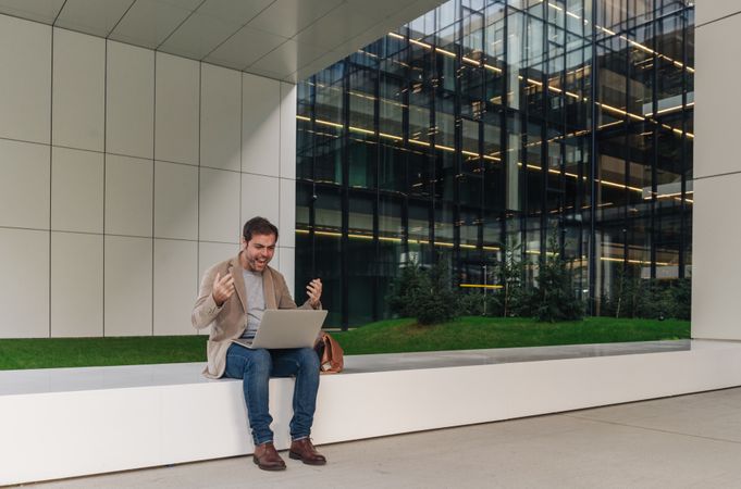 Cheerful businessman using laptop on street