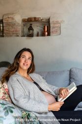 Pregnant woman lounging on sofa with book 5rp3nb