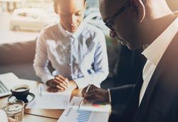Black man and woman analyzing charts in a cafe