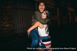 Night shot young woman lifting her best friend laughing 5arzW4