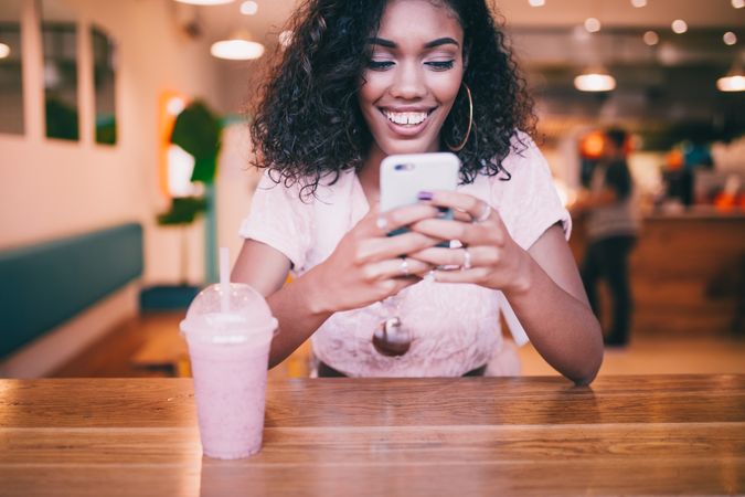 Young woman sitting at a table with a shake and a mobile phone