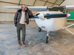 Confident pilot beside retro plane in hangar