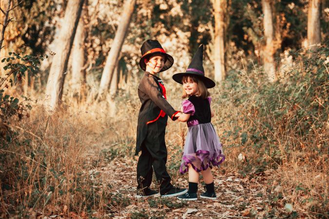 Brother and sister walking into forest in halloween costumes
