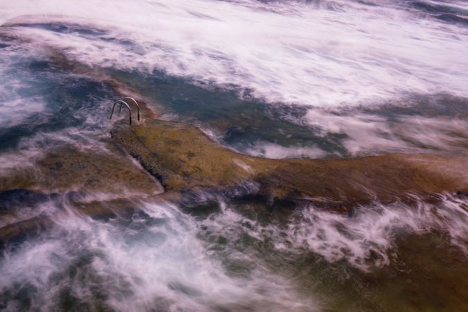 Stone shore with ladder between water
