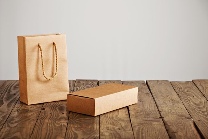 Cardboard box and matching gift bag on wooden table