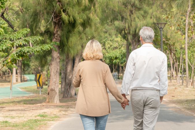 Rear shot of cute older couple walking hand and hand