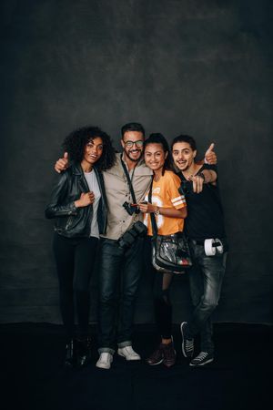 Studio shot of photographer standing with his arms around his crew