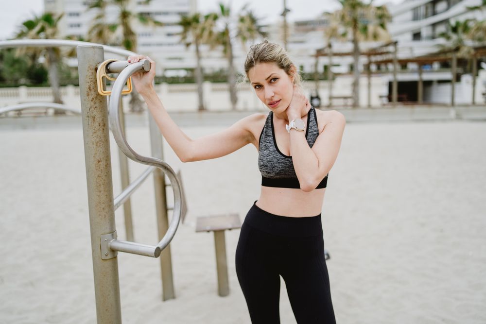 Sportswoman resting after workout in a sandy beach