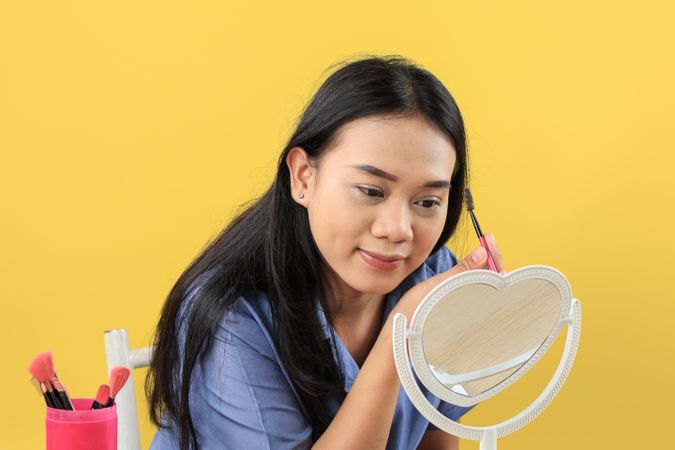 Smiling Asian Young Woman Brushing Eyebrows with Makeup Brush.