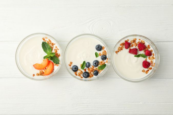 Flat lay composition with yogurt desserts and ingredients on  wooden background