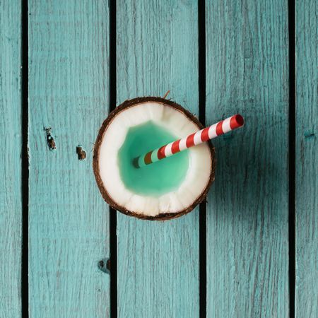 Coconut drink with straw on blue wooden background