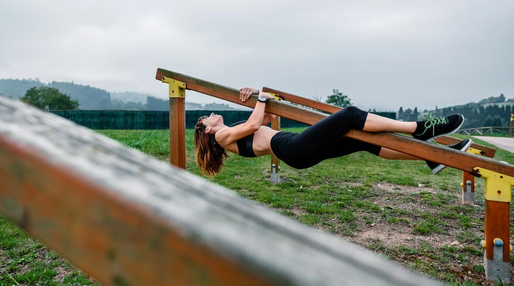 Sportswoman training hanging on a wooden bar