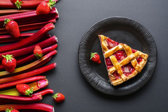 Close up slice of rhubarb-strawberry pie next to ingredients