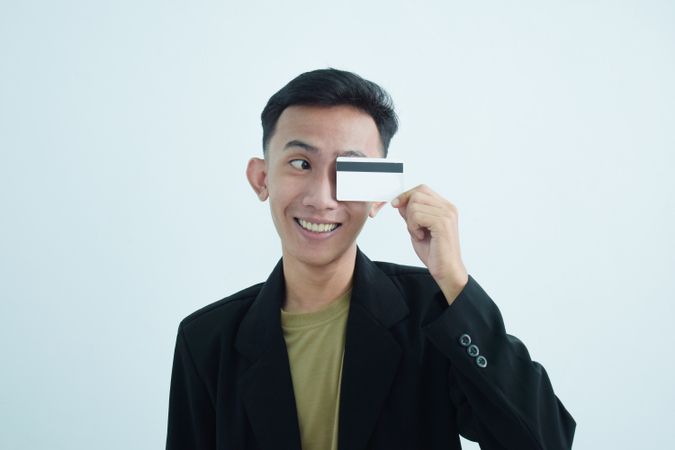 Asian young businessman wearing suit with tshirt and holding blank credit card