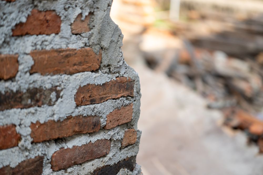 Half-collapsed brick wall with rough unfinished cement