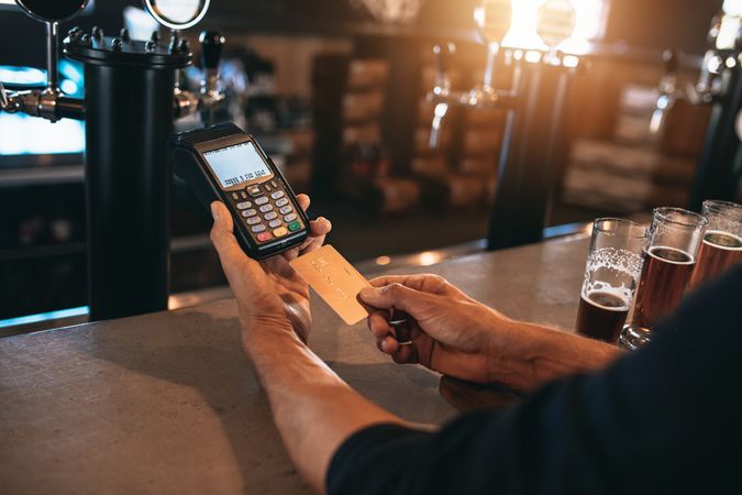 Cropped image of man paying using credit card at bar
