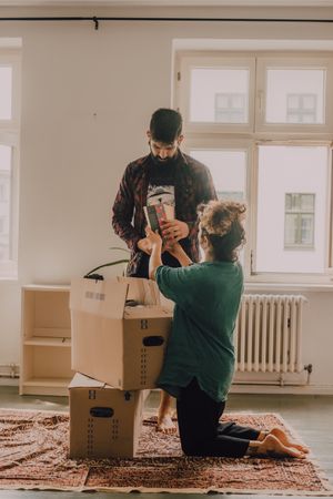 Casual couple unpacking boxes in apartment