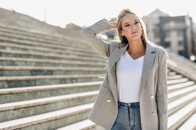 Woman in suit standing by outdoor steps on sunny day