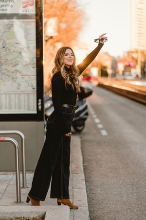 Cheerful woman hailing taxi